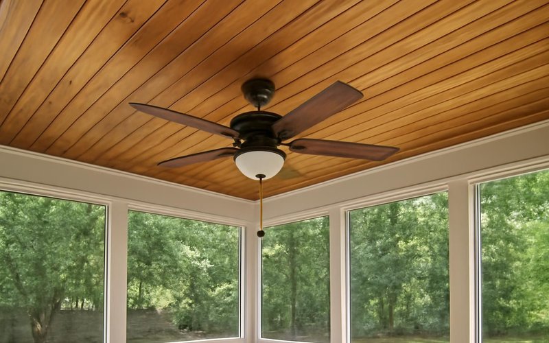 Stained tongue-and-groove porch ceiling with a fan